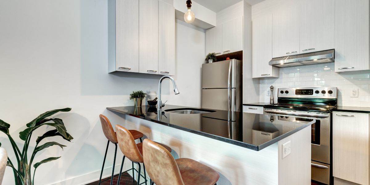 Modern kitchen with a black countertop, white cabinets, and stainless steel appliances.