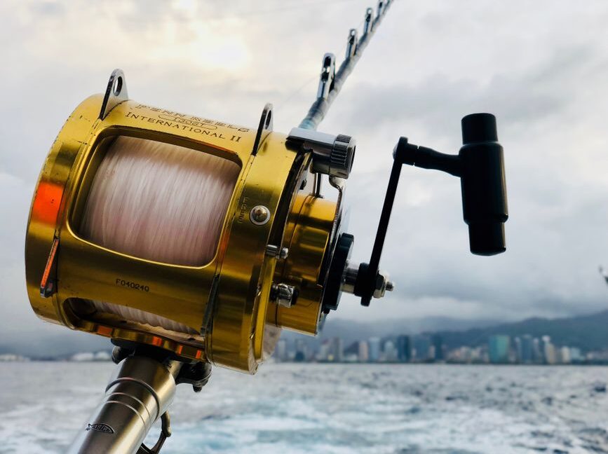 Angler on a boat in the deep blue ocean, battling a large game fish on the line with water splashing, showcasing the thril...