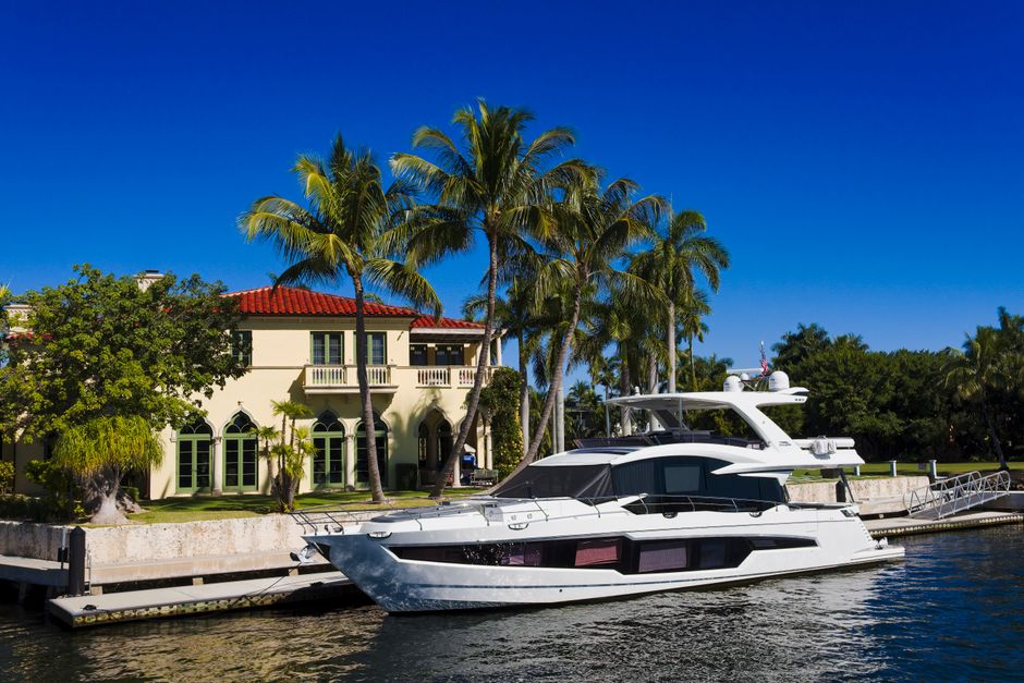 A beautiful, high-end sportfishing yacht docked in a sunny, tropical marina with lush green mountains in the background, representing a luxury fishing vacation in Puerto Vallarta.