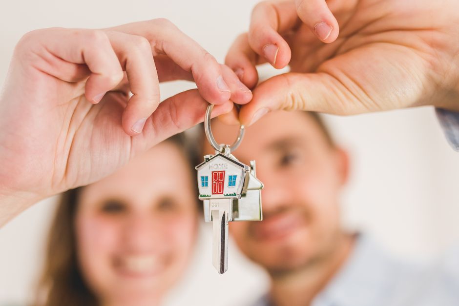A close-up, professional shot of one person's hand giving a set of modern house keys to another, symbolizing a successful, high-value transaction.