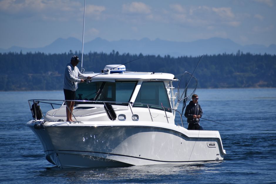 A proud angler on the deck of a fishing boat, holding up a massive yellowfin tuna, symbolizing the trophy catch of a rugged offshore fishing expedition.